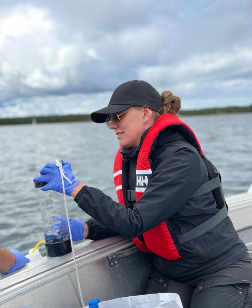 en kvinna i en båt tar vattenprover