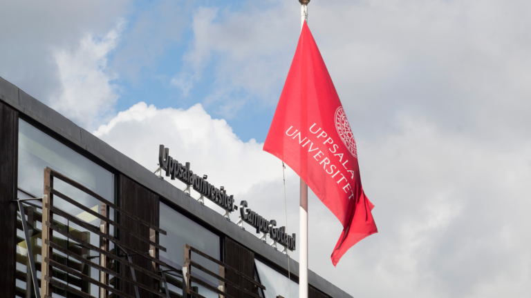 Flagga och skylt på fasad med texten Uppsala universitet